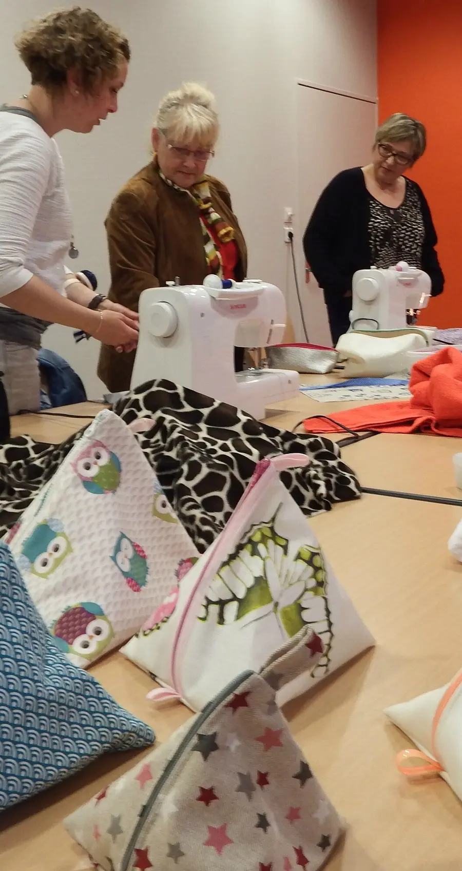 Cours de couture à la Maison de quartier Robert Manceau : trois couturières autour des machines, des trousses terminées sur la table